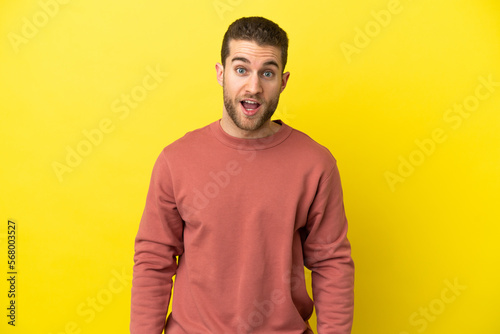 Handsome blonde man over isolated yellow background with surprise facial expression