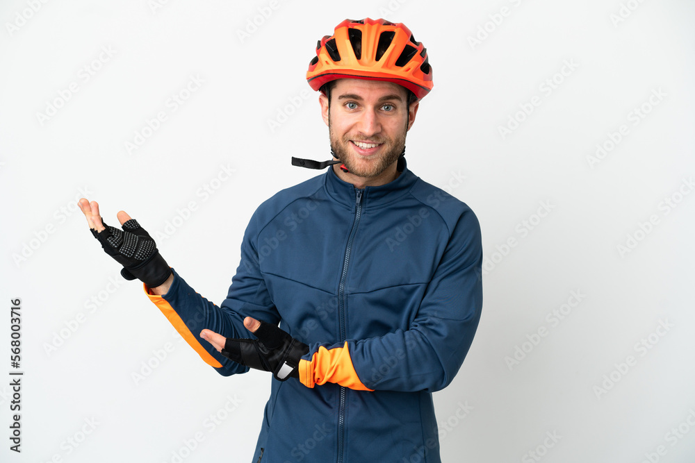 Young cyclist man isolated on white background extending hands to the side for inviting to come