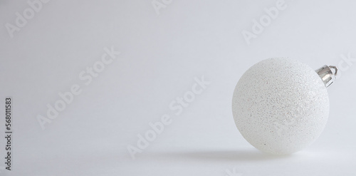white christmas ball with silver sparkles on gray background