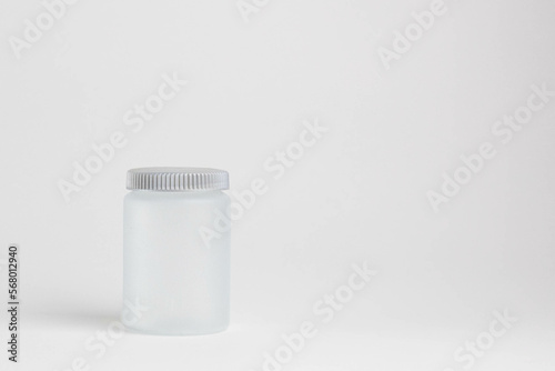 A light gray medicine jar stands on a light background