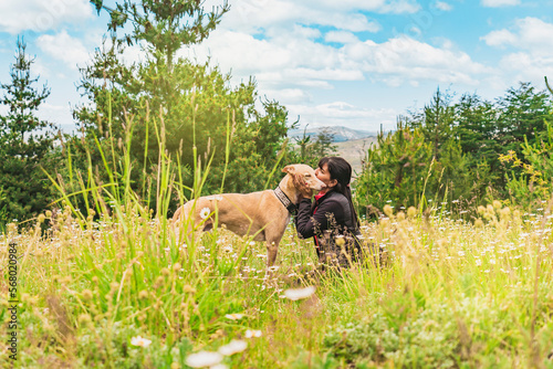 Beautiful woman kissing her greyhound dog outdoors.