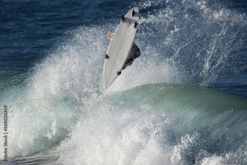Obraz premium A surfer executes a radical aerial move on as he surfs a wave in the ocean.