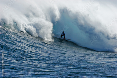 A surfer is enveloped by the foam of a huge wave while surfing in the ocean.