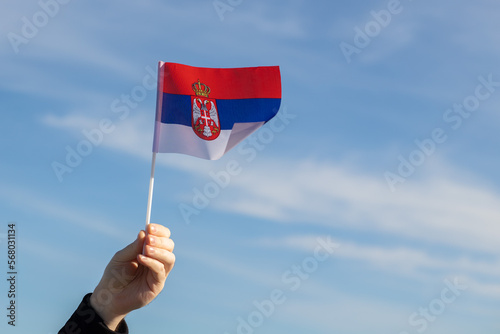Obraz na plátně Serbian flag in hand flutters in the wind against the sky, independence national