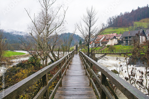 Hudiceva Brv Bridge, the Devil's Footbridge, crossing over Poljanska Sora river in Skofja Loka, Gorenjska, Slovenia. The river is very full due to heavy rain. There is a small shrine in the centre