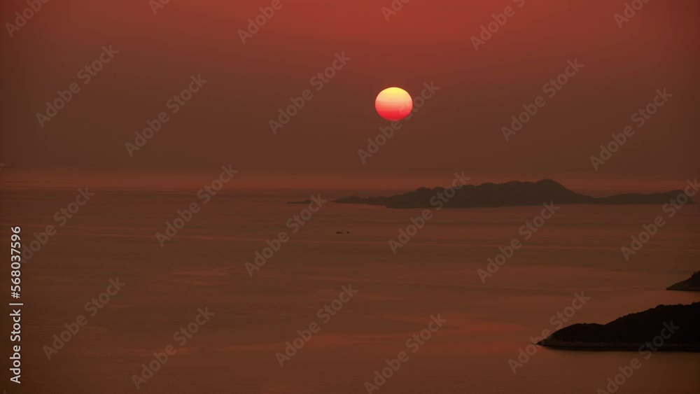 Calm sunset over sea. Orange sky with sun going down into sea Calm sunset over sea. Orange sky with sun going down into sea