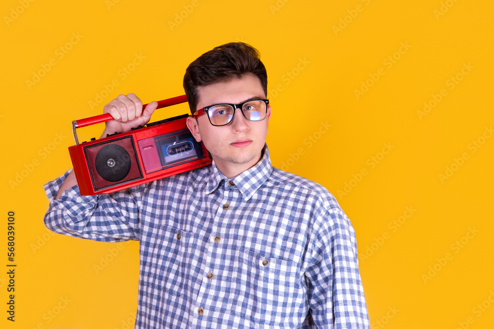 A handsome guy in glasses and with boombox on a yellow background A handsome guy in glasses and with boombox on a yellow background