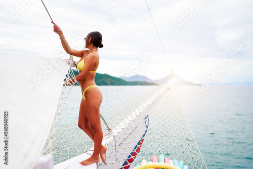 portrait beautiful young brazilian woman standing in a swimsuit on the bow of a boat in Ilha Grande Brazil photo