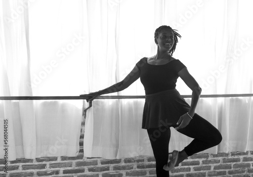 A Black American female dancer, holding a ballet position on the barre at a dance studio in Bali, Indonesia 