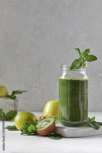 Green smoothie with spinach, banana, kiwi, apple and mint in a glass jar decorated with mint. Delicious and healthy breakfast. 
