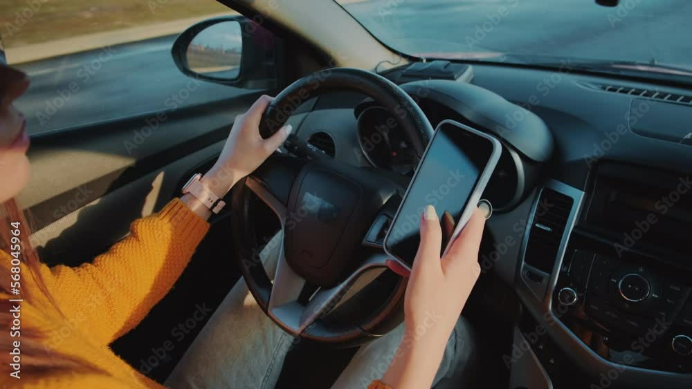 Young woman driver using mobile phone while driving car in motion, distracted driving, don't text and drive
