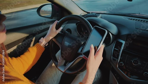 Young woman driver using mobile phone while driving car in motion, distracted driving, don't text and drive