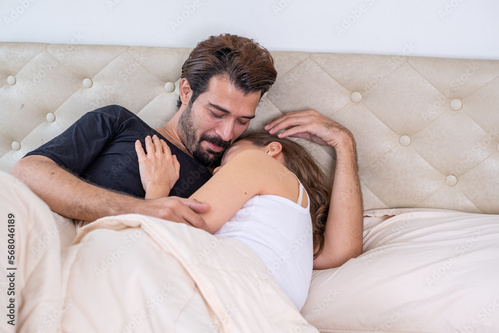 Young couple in a relationship kissing and cuddling. Happy couple hug and kiss on the bed near the window in the morning. Sensual young couple kissing on bed at home. Young couple in a relationship kissing and cuddling. Happy couple hug and kiss on the bed near the window in the morning. Sensual young couple kissing on bed at home.