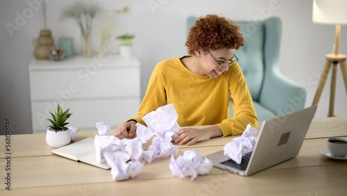Girl does studies, work or writes on piece paper. Failure on career, unable do job. Young woman gets angry, crumpled and throw sheet of paper on table. Unproductiveness, frustration, burnout on work. photo