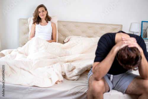 Young couple having problems with sex life. Couple quarreling and fighting in relationship at home. Relationship problems. Man sitting on the edge of the bed in bedroom.