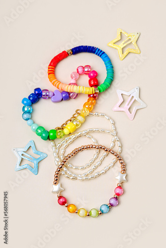 Kids handmade beaded jewelry. Necklaces and bracelets made from multicolored beads and pearls on a pastel background. DIY Multi-colored bracelet beads. Children's needlework