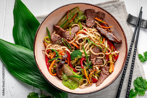 Tela Udon stir fry noodles with beef meat and vegetables in a plate on white wooden background
