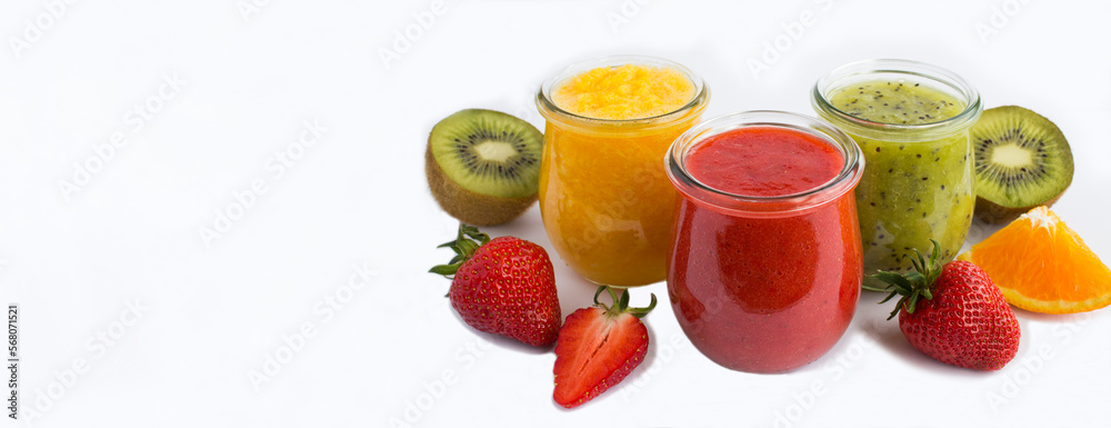 Smoothie or puree with fruit and berry in the small glass jars on the white background. Copy space. Banner. Smoothie or puree with fruit and berry in the small glass jars on the white background. Copy space. Banner.