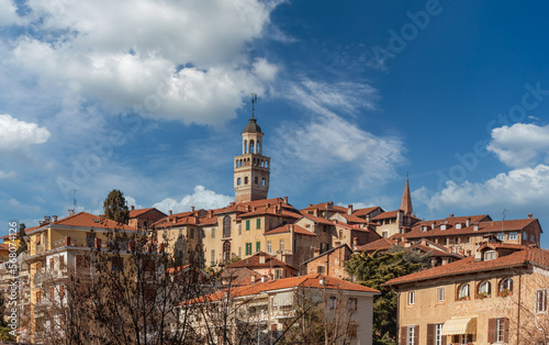 Landscape of the medieval village with the civic tower in Saluzzo, Piedmont, Italy, on blue sky with white clouds