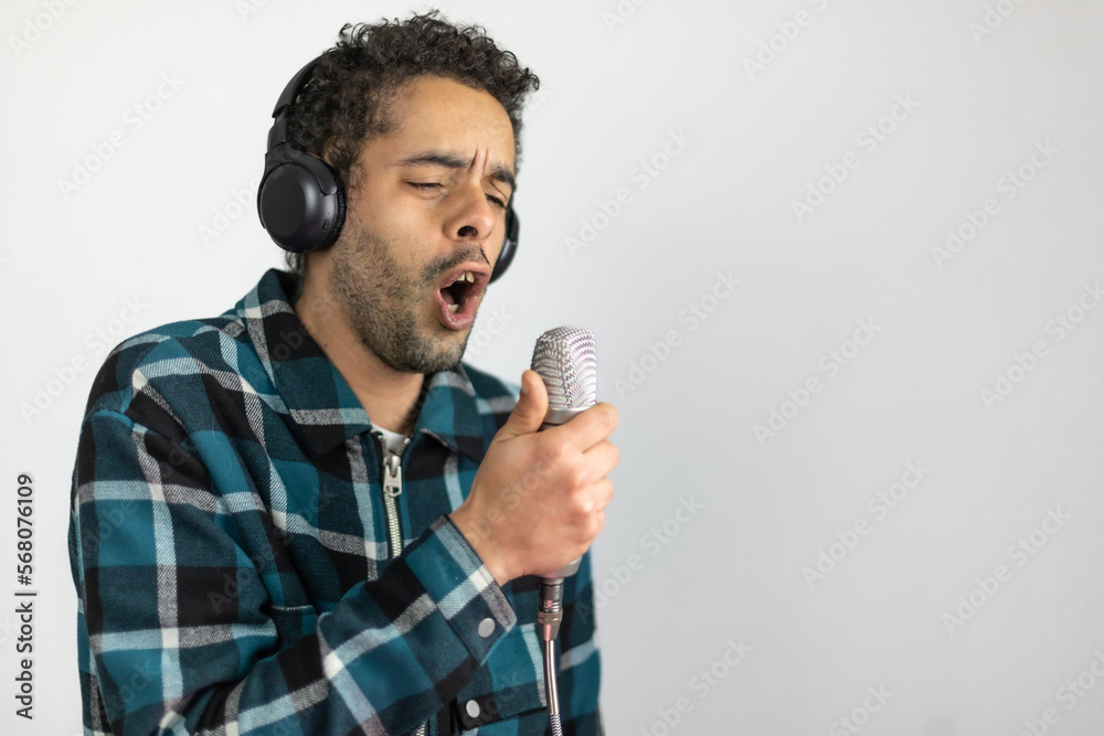 Mixed race man dressed in checked shirt singing into a condenser microphone Mixed race man dressed in checked shirt singing into a condenser microphone