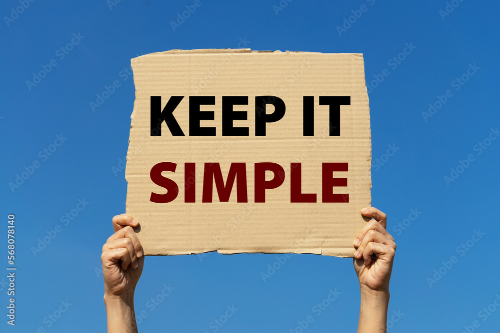 Keep it simple poster held by 2 hands with isolated blue sky background Keep it simple poster held by 2 hands with isolated blue sky background