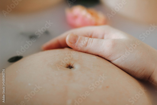Cropped view of pregnant woman taking bath with flowers and milk