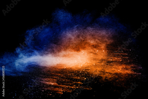 Orange blue powder explosion on black background.Orange blue color dust splashing.