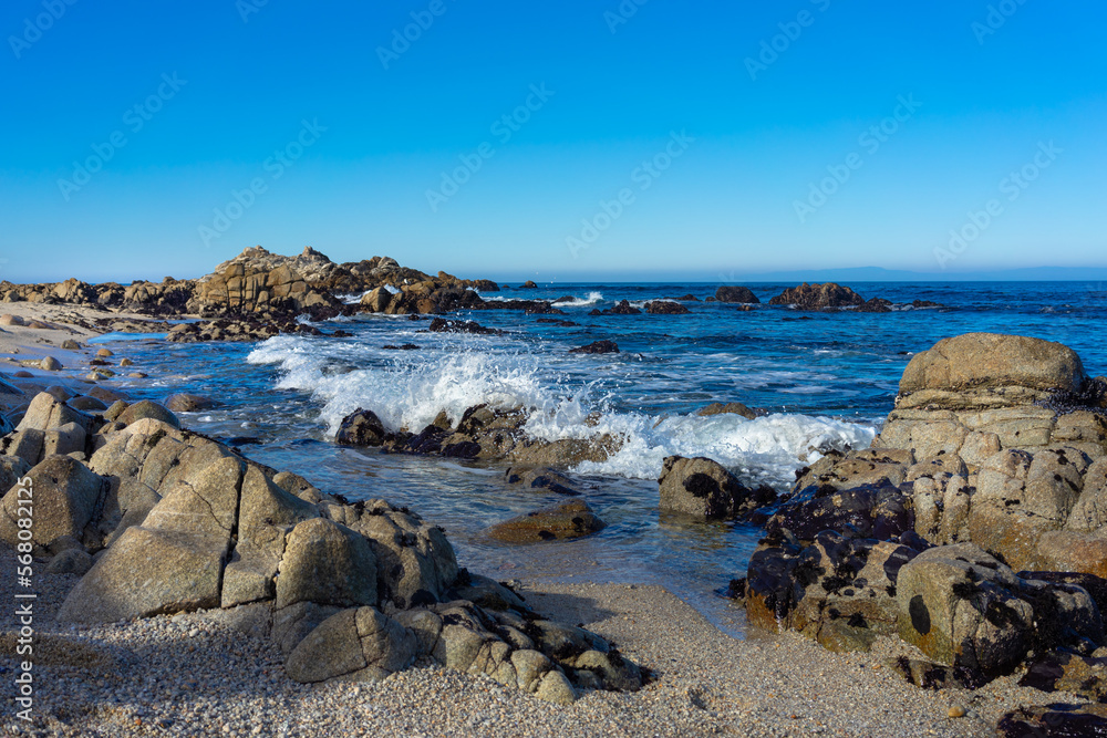 Beach with rock formations and crashing ocean wave at Monterey Bay