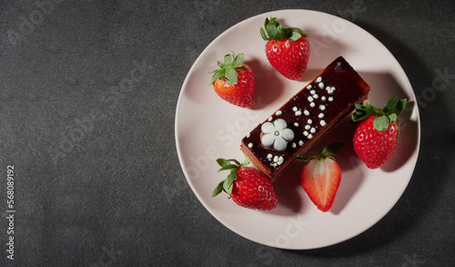 Three chocolates cake with chocolate drips on a black background. Layered cake with milk, black and white chocolate souffle decorated with strawberries on top. Confectionery background with copy space