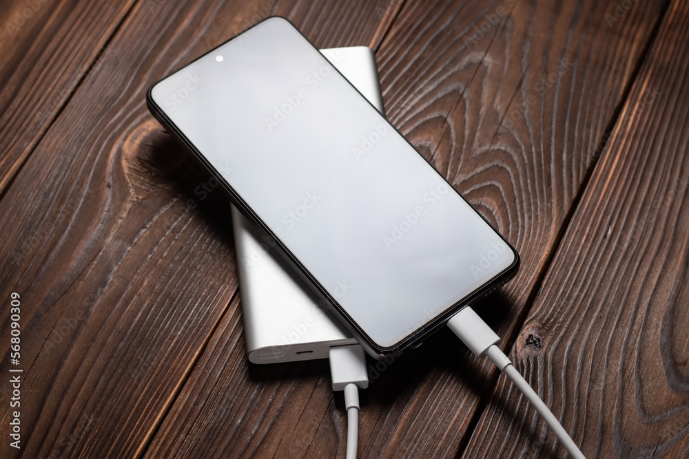 white power bank and smartphone on wooden background. white power bank and smartphone on wooden background.