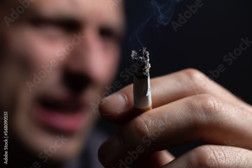 Passive smoking concept. Man is smoking cigarette and other man expresses dissatisfaction with his face.