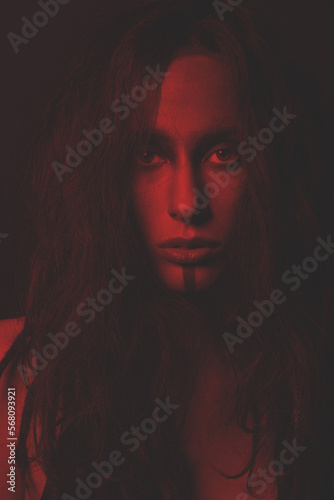 Beauty and make-up concept. Beautiful woman studio portrait. Model with messy dreadlocks hair and make-up looking to camera with seductive look. Toned image with red and black color