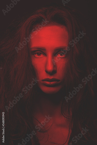 Fashion and make-up concept. Studio portrait of beautiful woman with eye shadows, long and dark dreadlocks hair looking at camera with seductive look. Toned image with red and black color