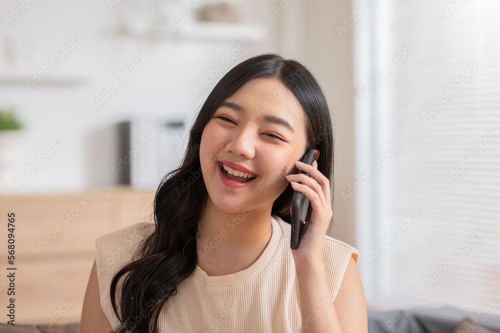 Asian young woman answer the phone and talking with positive and happiness emotional.Attractive female talkin in smartphone smile and cheeful with good news and good moment at home Asian young woman answer the phone and talking with positive and happiness emotional.Attractive female talkin in smartphone smile and cheeful with good news and good moment at home