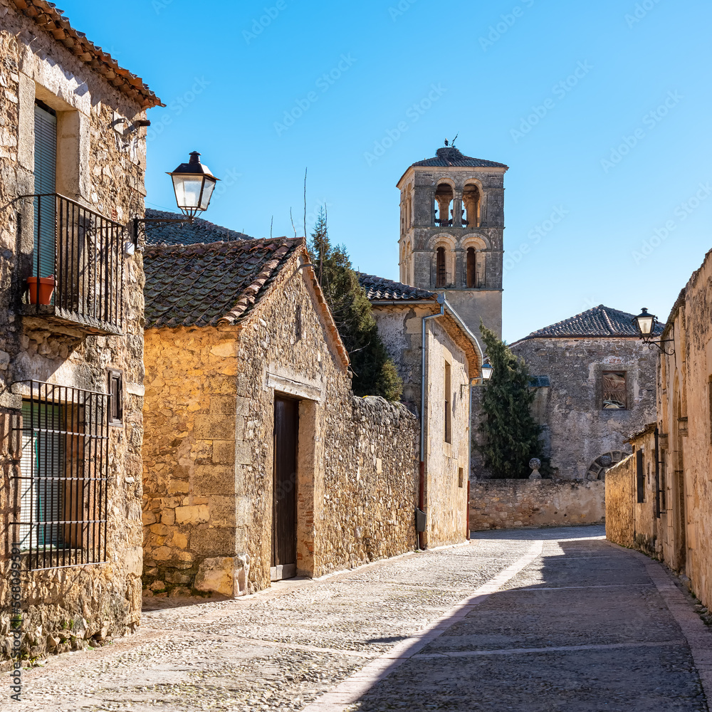 Obraz premium Street of beautiful medieval buildings with church tower in the background in the monumental city of Pedraza, Segovia, Spain.
