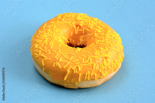round mango donut with sugar sprinkles isolated on blue background, macro