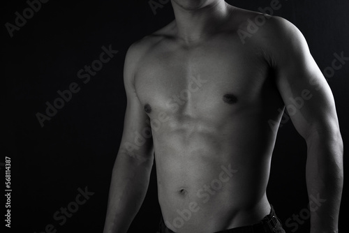 Close up view of sexy body of young man with six pack muscular and athletic body on black background. concept of health care, exercise, fitness, muscle mass, health supplements.