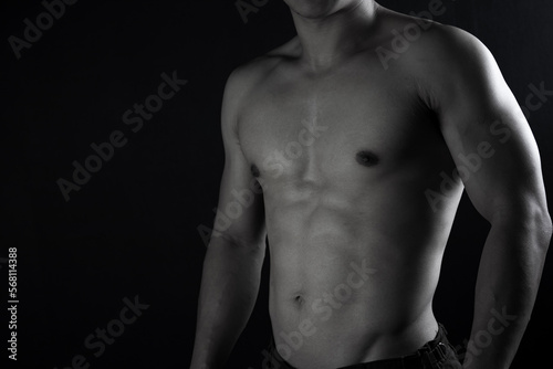 Close up view of sexy body of young man with six pack muscular and athletic body on black background. concept of health care, exercise, fitness, muscle mass, health supplements.