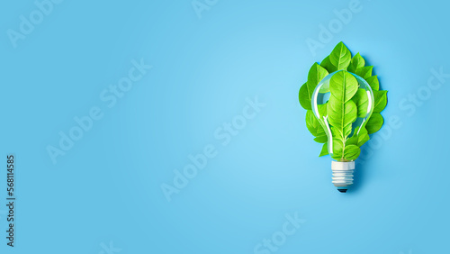 Green energy concept. Energy saving technology, light bulb with green leaves on blue background Space for text on the left
