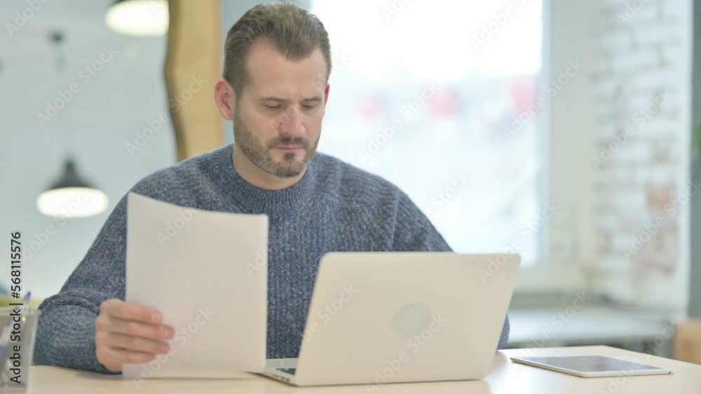 Middle Aged Man Working on Laptop and Documents Middle Aged Man Working on Laptop and Documents