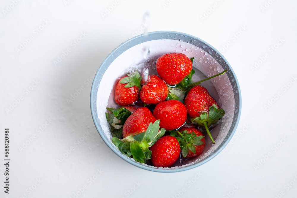 Water pouring into bowl with red strawberries Water pouring into bowl with red strawberries