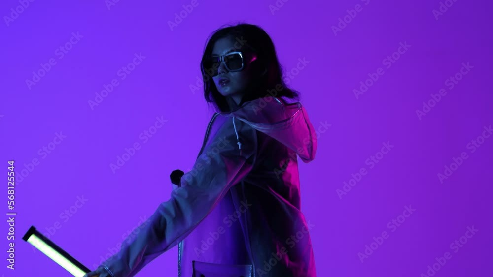 Woman in futuristic costume. Female in modern VR glasses interacting with network while having virtual reality experience. Augmented reality game, future technology, AI concept. VR. Neon light. Woman in futuristic costume. Female in modern VR glasses interacting with network while having virtual reality experience. Augmented reality game, future technology, AI concept. VR. Neon light.
