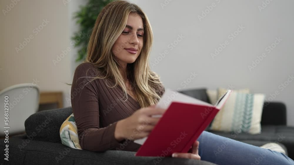 Young blonde woman reading book sitting on sofa at home Young blonde woman reading book sitting on sofa at home