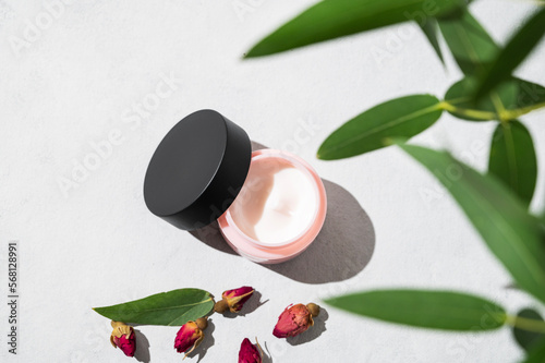 Face and body cream on a light background with shadow. The concept of care cosmetics with rose and eucaliptus. Health and beauty.