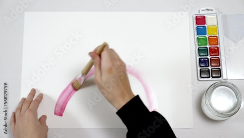 A teenager's hands draw a rainbow with watercolors. LGBT symbol. Timelapse. photo