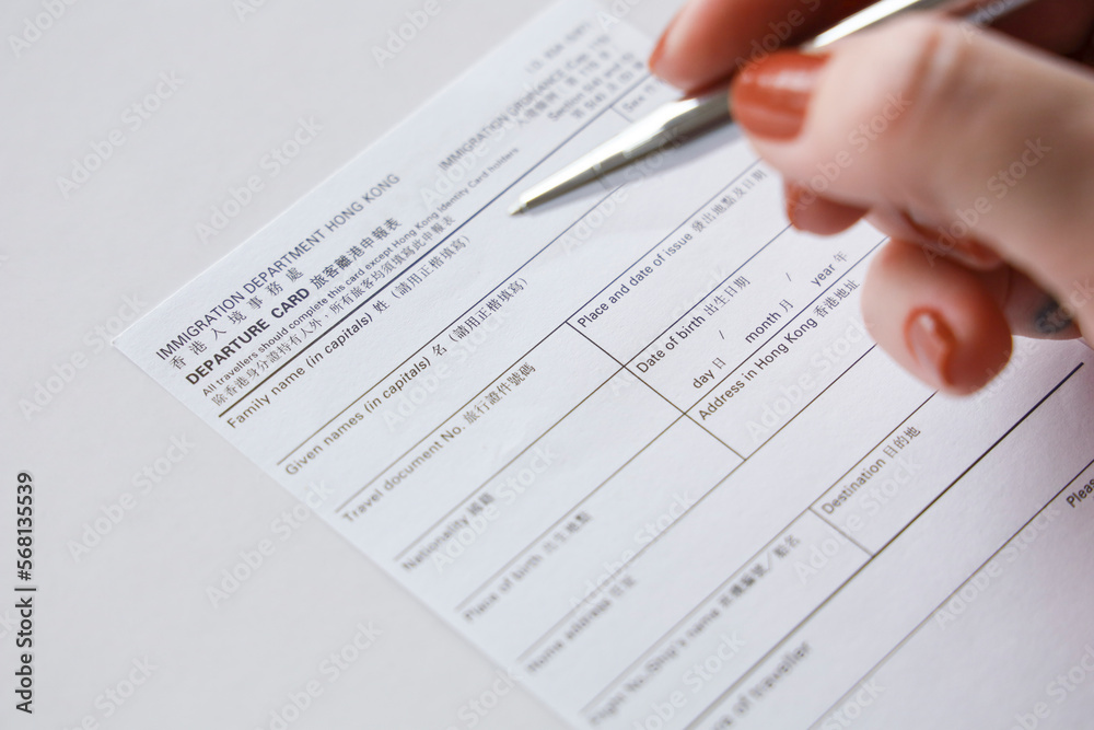 HONG KONG, CHINA, FEBRUARY 2020 - Tourist hand filling departure card at the immigration checkpoint at the airport