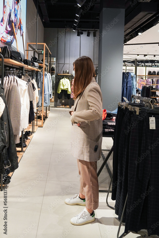 Beautiful woman is wearing protective face mask in shopping center. Girl trying on clothes. Concept of virus protection. Fashion, beauty and shopping concept. Beautiful woman is wearing protective face mask in shopping center. Girl trying on clothes. Concept of virus protection. Fashion, beauty and shopping concept.