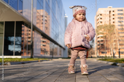 Small caucasian girl toddler stand in the city outdoor in winter day
