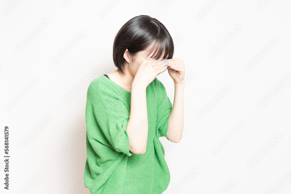 白背景の前で泣いている若い女性