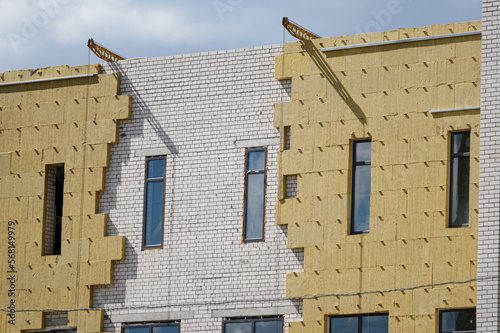 Sheathing of the outer wall of a brick building with insulation. Insulation of the facade of the building. The concept of exterior finish, moisture protection,sound insulation,energy saving.